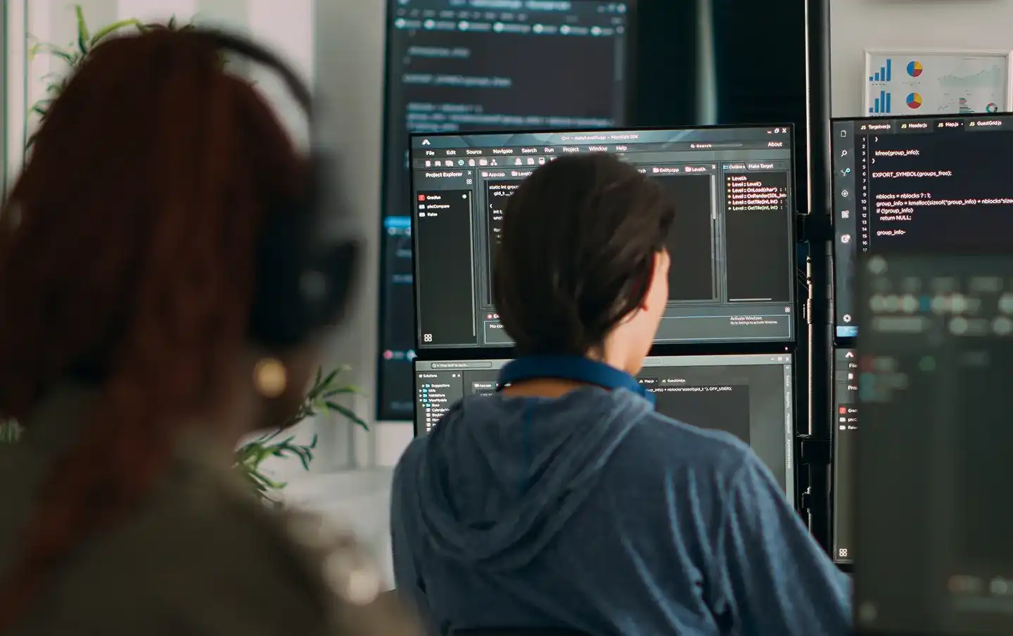 Software developer writing code across multiple monitors in a modern office, illustrating DevOps managed services built for reliable, continuous software delivery